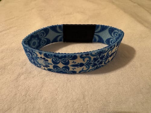Customer's blue and white patterned Make It A Good Day Bracelet on a white cloth, showing the inner band.