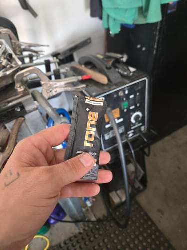 Reviewer holding a single packet of SuperCharged Honey in what appears to be a workshop.