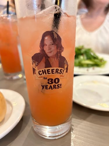 Customer's custom 'Cheers to 30 Years' birthday tattoo applied to the side of a drink glass.