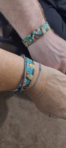 Customer's wrists shown side-by-side, each wearing a matching colorful Side By Side Bracelet with an otter print.