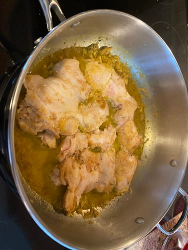 Customer cooking Organic Boneless & Skinless Chicken Thighs in a large stainless steel pan on a stovetop.