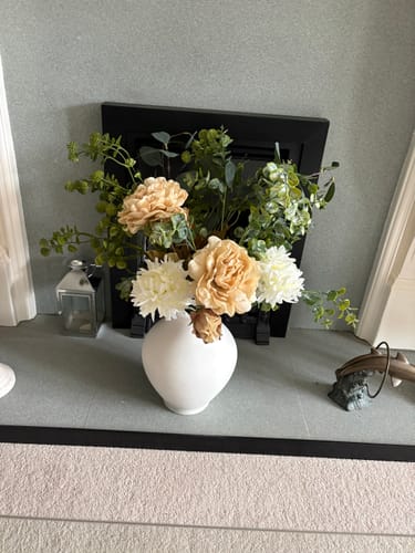 Customer's Faux Arrangement with cream and white flowers in a white vase on a mantelpiece.