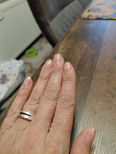 Hand einer Kundin, die die glänzenden 'Candy Sorbet' UV-Gel-Nagelfolien auf kurzen, natürlich aussehenden Nägeln zeigt.
