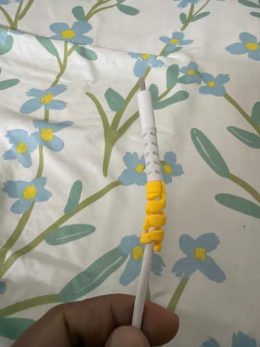Reviewer's hand holding a white cable with the yellow Cable Protector wrapped around the end.