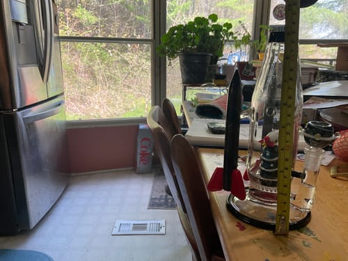 Customer measures their Empire Glassworks Rocket Ship Bong with a tape measure on a wooden table.