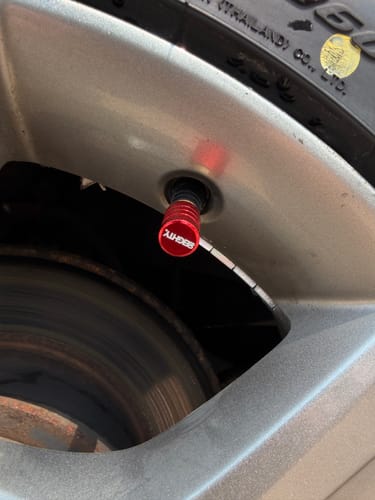 Customer's close-up of a red 80Eighty valve stem cap installed on a car tire.