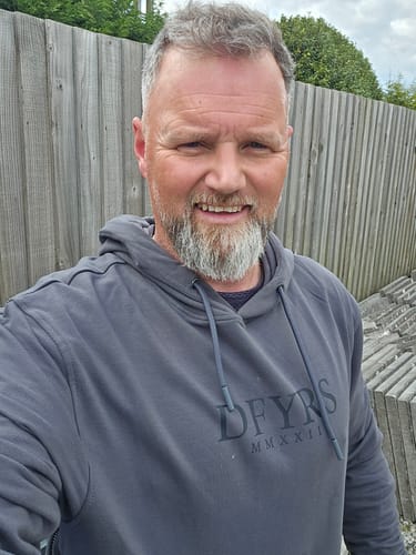 Customer smiling while wearing the grey Tarot Trailhood hoodie outdoors.