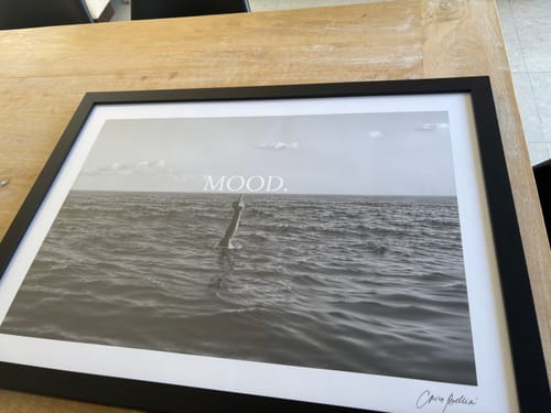 Customer's MOOD art print in a black frame, displayed on a wooden table.