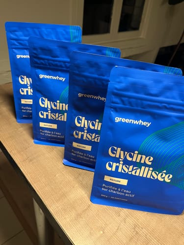 Photo d'un client montrant quatre sachets bleus de Glycine cristallisée alignés sur une table.