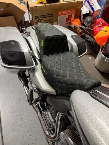 Close-up of customer's black Born Scum X Saddlemen Step Up Seat with green stitching installed on a silver motorcycle.