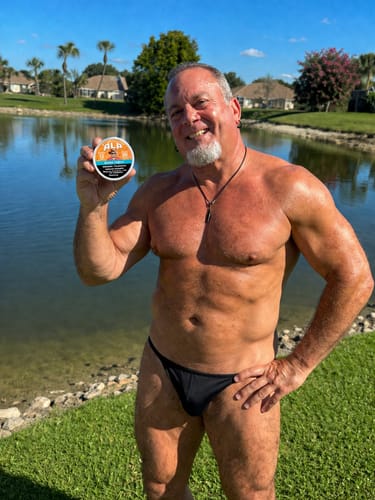 Reviewer holding a can of Drifters Mango Freeze Nicotine Pouches outdoors by the water.