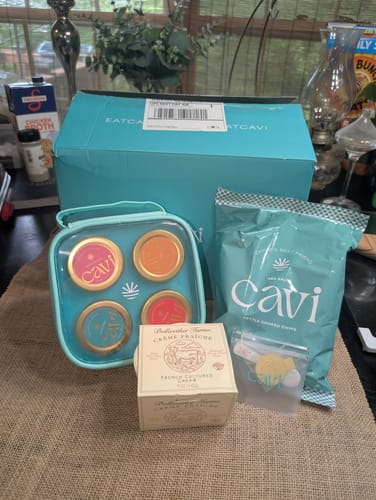 Customer's unboxed CAVI's Beginner Tasting Kit showing the caviar tins, chips, and crème fraîche on a table.