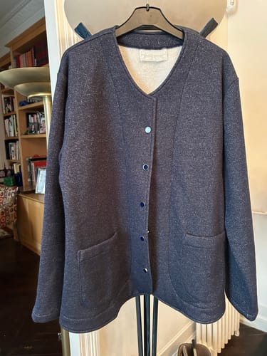 Photo d'un client de la Veste Nathalie bleu marine pailleté, suspendue sur un cintre à l'intérieur.