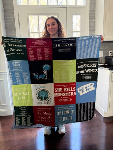 Customer holding their finished Project Repat T-Shirt Quilt, made from various theater and dance event shirts.