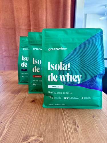 Avis d'un client : trois sachets verts d'Isolat de Whey Native, saveurs vanille et chocolat, posés sur une table en bois.