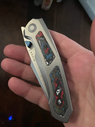 Customer holding the folded Kizer Feweed XL knife, showing its titanium handle and colorful Nebula Fat Carbon inlays.