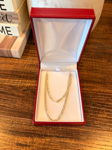 Customer's 14k Solid Cuban Curb Chain displayed in an open red jewelry box on a wooden surface.