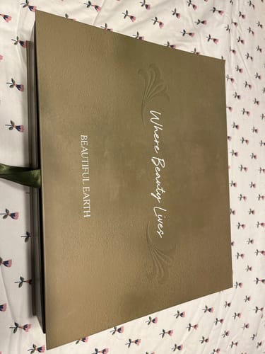 Customer's elegant brown Spring Box Packaging lying closed on a floral fabric.