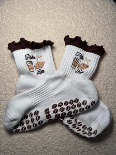 Customer's pair of Pilates & Lattes socks, showing the embroidery and coffee-bean-shaped grips on the soles.