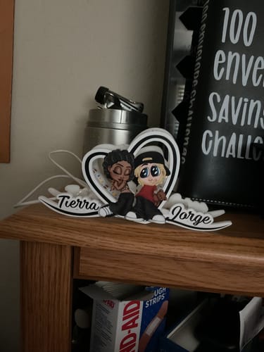Customer's personalized heart-shaped light box with the names 'Tierra' and 'Jorge' unlit on a wooden shelf.