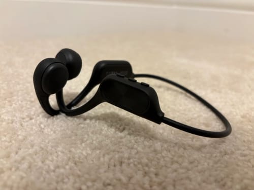 Recensore mostra le cuffie nere AirBeat WaterProof su un tappeto.