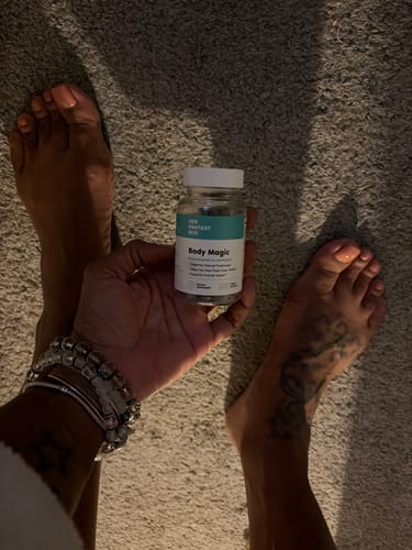 Customer holding a bottle of Body Magic Chlorophyll Pills, viewed from above on a grey carpet.