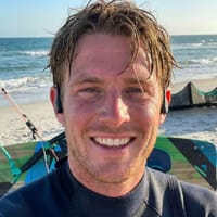 Cliente sorridente in spiaggia che indossa le cuffie nere AirBeat WaterProof.