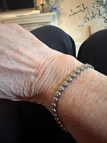 A reviewer shows the silver-toned Classic Bezel Tennis Bracelet worn on their wrist.