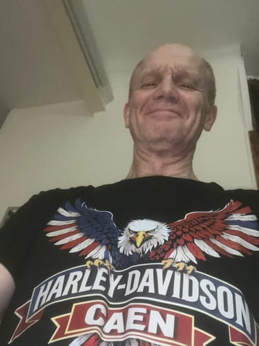 Client souriant qui porte le T-shirt Aigle HDC noir avec son motif d'aigle.