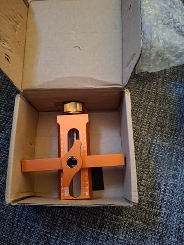 Reviewer's orange cabinet door installation aid sitting alone inside its shipping box.