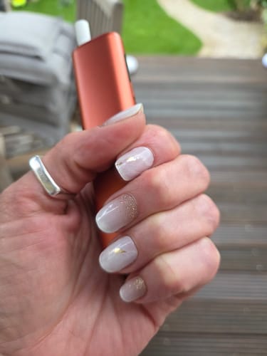 Hand einer Kundin, die die 'Gold Rush Marble' UV-Gel-Nagelfolien mit einem rosa Marmordesign und goldenen Akzenten trägt.