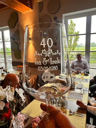 Ein Kunde hält ein personalisiertes Leonardo Weinglas mit der Gravur „40“ in einem Restaurant.