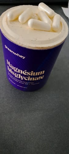 Photo d'un client montrant le pot violet de Magnésium Bisglycinate avec des gélules blanches posées sur le couvercle.