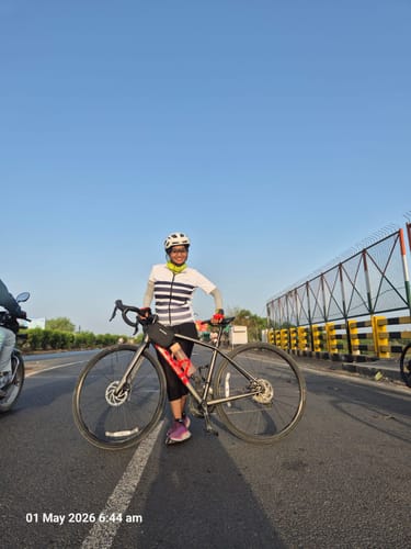 Reviewer, an active athlete, standing with their bicycle on a paved road under a clear sky.