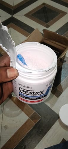 Customer opening a new tub of Wellcore Micronised Creatine Monohydrate, showing the pink powder inside.