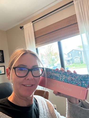 Reviewer holding up a pink and sparkly Weekly AM-PM Vitamin Case with the text "Rise & shine" on the side.