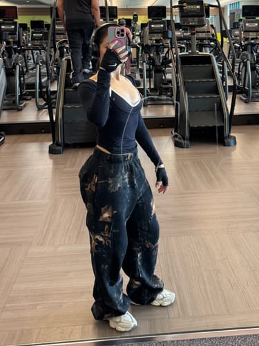 Reviewer taking a mirror selfie at the gym wearing the oversized Camo Cargo Joggers.
