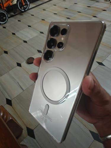 Reviewer holding their Samsung phone in the clear Magsafe case, showing the back and the magnetic ring.