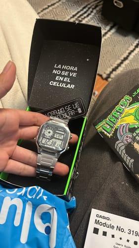 Un cliente sostiene en la mano el reloj Casio Vintage plateado sobre su caja de embalaje abierta.