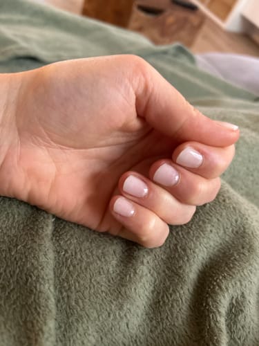 Eine Kundin zeigt ihre Hand mit den Babyboomer Semi Transparent UV Gel-Nagelfolien auf kurzen, gepflegten Nägeln.