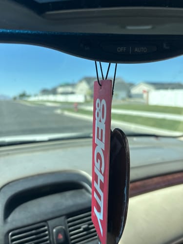 Customer's red 80Eighty Air Freshener hanging from a car's rearview mirror.