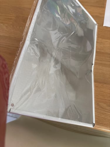 Customer's Funny Wall Art sign, still in its plastic sleeve, showing it arrived severely bent and creased.