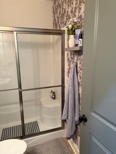 Customer photo showing the Lilac Wallpaper used as a stylish accent wall in a bathroom next to a shower.