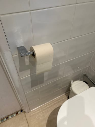 Customer's roll of Unbleached Bamboo Toilet Paper on a holder in a tiled bathroom.