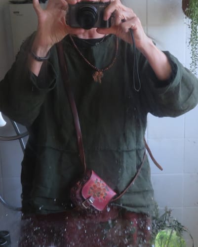 Reviewer wearing the dark green linen blouse layered over a shirt in a mirror selfie.