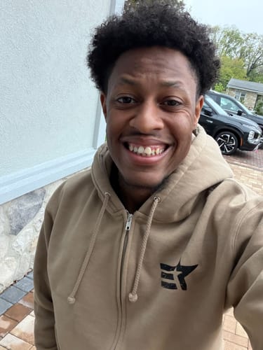 Reviewer smiling while wearing the tan zip-up hoodie from their ENR#80 Exclusive Mystery Box.