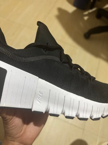 Customer holding a black Nike Free Metcon 6 shoe, showing the creased white midsole.