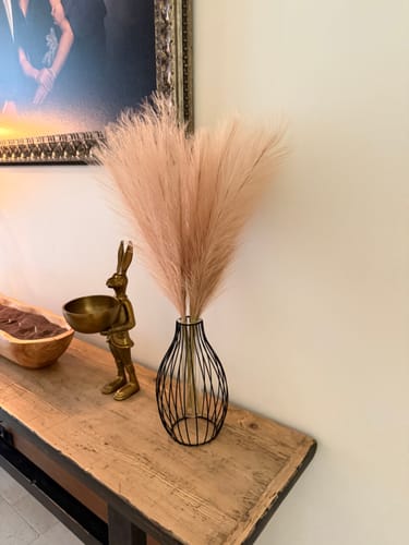 Customer's Natural Rose Faux Pampas Grass in a black wire vase on a wooden console table.