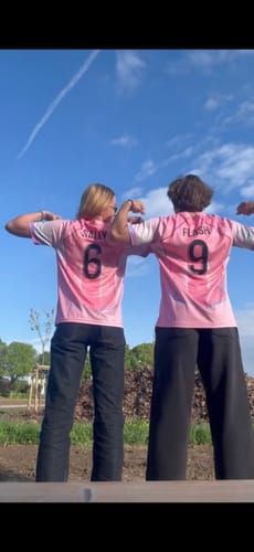 Deux clients portant le maillot PSG Concept 25/26 rose en extérieur, vus de dos.