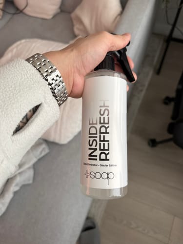 Customer holding a bottle of +Soap Inside Refresh Glacier spray in their home.